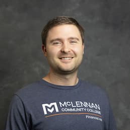 Smiling man in a studio-style headshot wearing a McLennan Community College T-shirt.